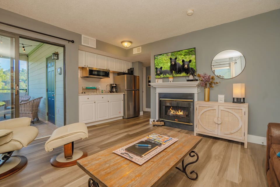 Your open-concept retreat blends kitchen, dining, and living areas with warm wood floors, a cozy fireplace, and a private balcony overlooking peaceful views—perfect for unwinding after a day exploring.