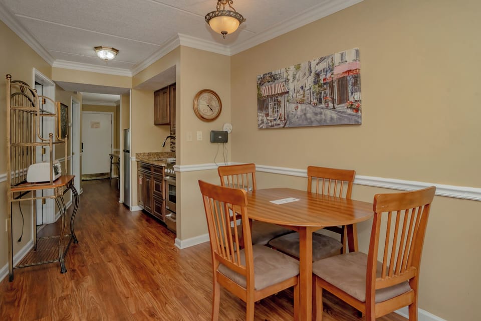 A welcoming dining area where you can share meals at a warm wood table for four, with rich hardwood floors underfoot and elegant lighting above.