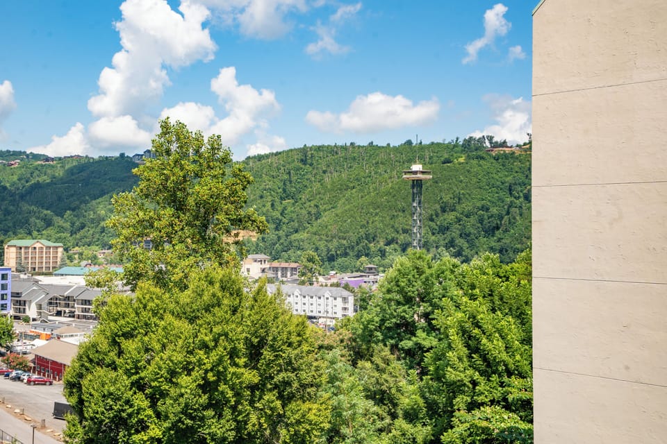The property sits near downtown Gatlinburg with the iconic Space Needle visible among lush tree-covered hills, offering easy access to local attractions and entertainment.