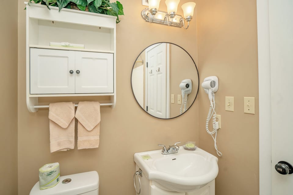 Freshen up in your private bathroom with plush towels, a lit vanity mirror, and hair dryers ready for your convenience.