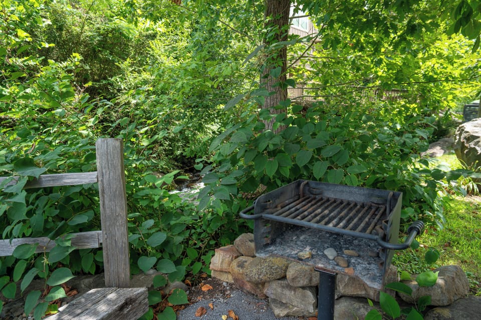 Tucked into lush greenery, this rustic outdoor BBQ space offers a peaceful spot to grill surrounded by vibrant trees and natural beauty.