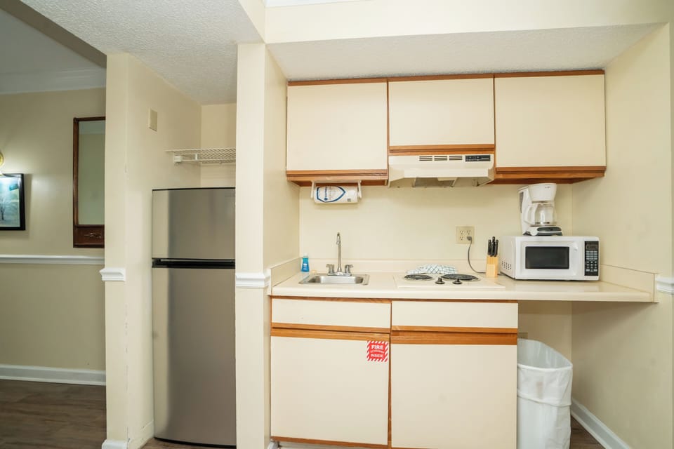 Step into your fully equipped kitchen, ready for preparing meals with a stove, microwave, refrigerator, and coffee maker—everything you need for a comfortable stay.