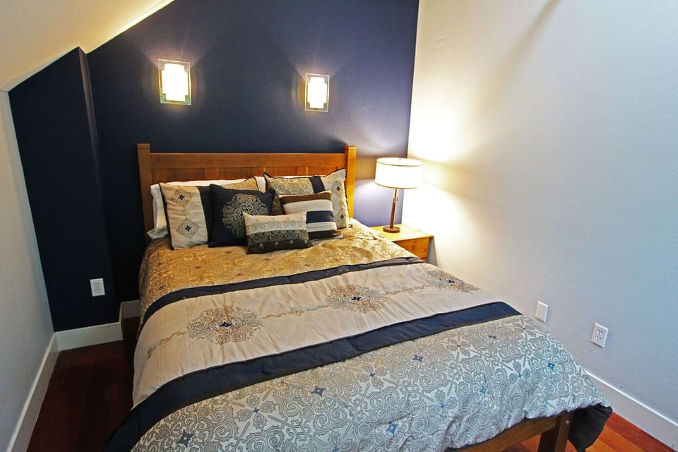 Master bedroom upstairs with TV, large windows, ceiling fan