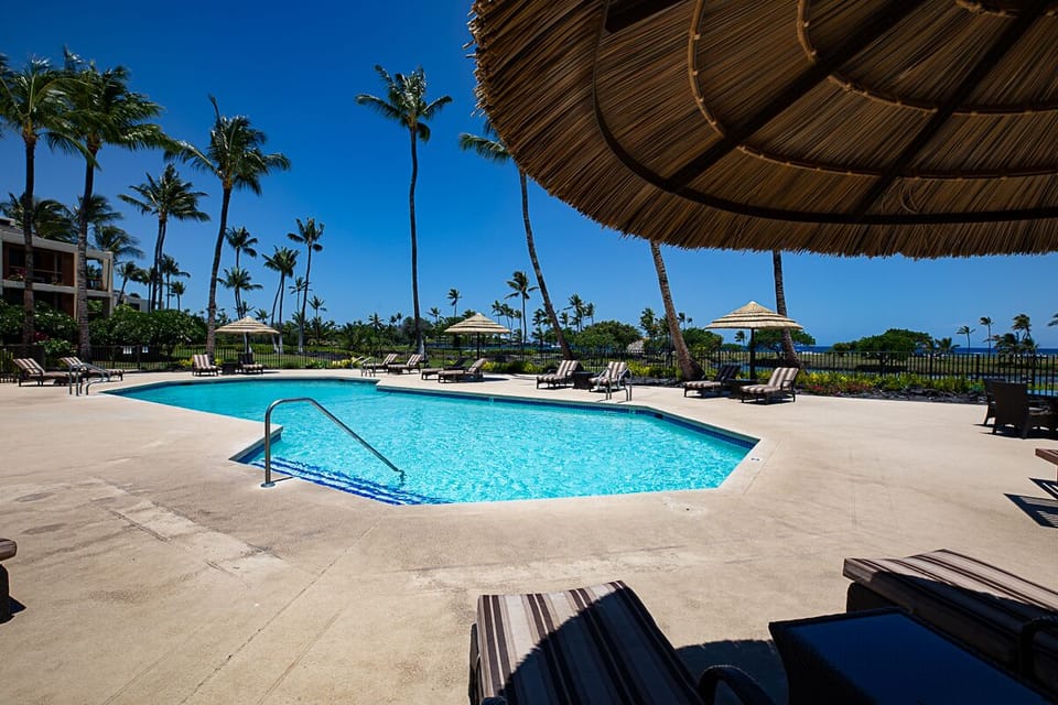 Take a refreshing dip in the Mauna Lani Terrace pool, surrounded by tropical landscapes and serene skies.