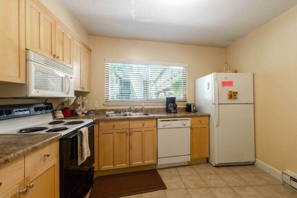 The charming kitchen is fully equipped with everything you need to whip up a meal, including a bar/island with seating for two, ample cabinet and counter space and natural light thanks to the over-the-window sink.