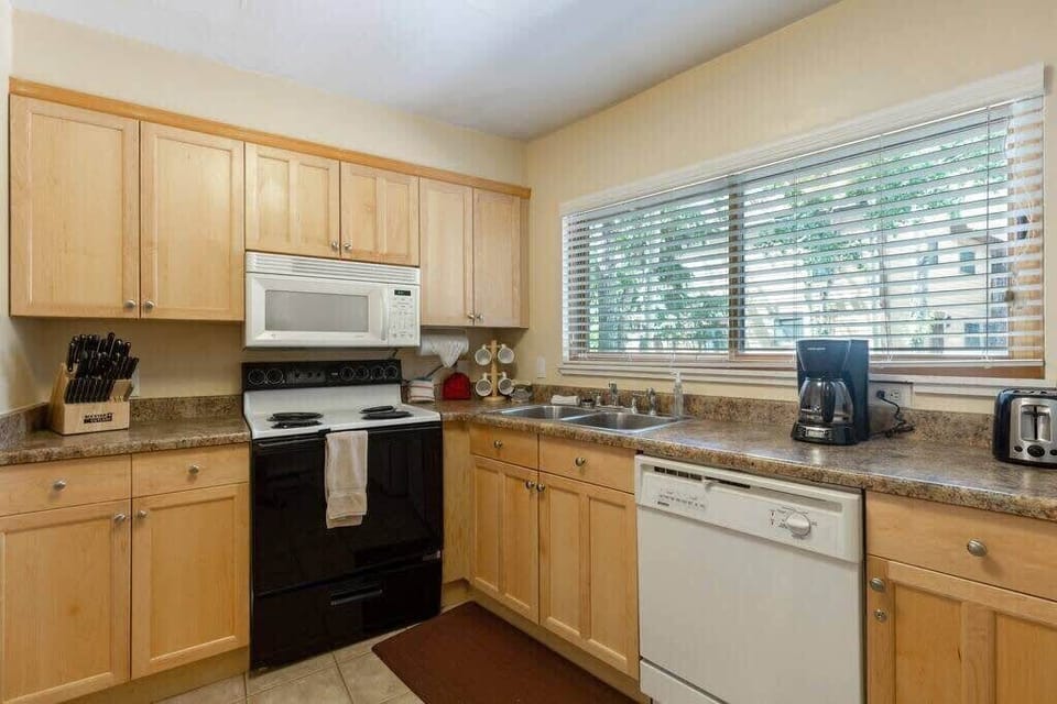 The charming kitchen is fully equipped with everything you need to whip up a meal, including a bar/island with seating for two, ample cabinet and counter space and natural light thanks to the over-the-window sink.