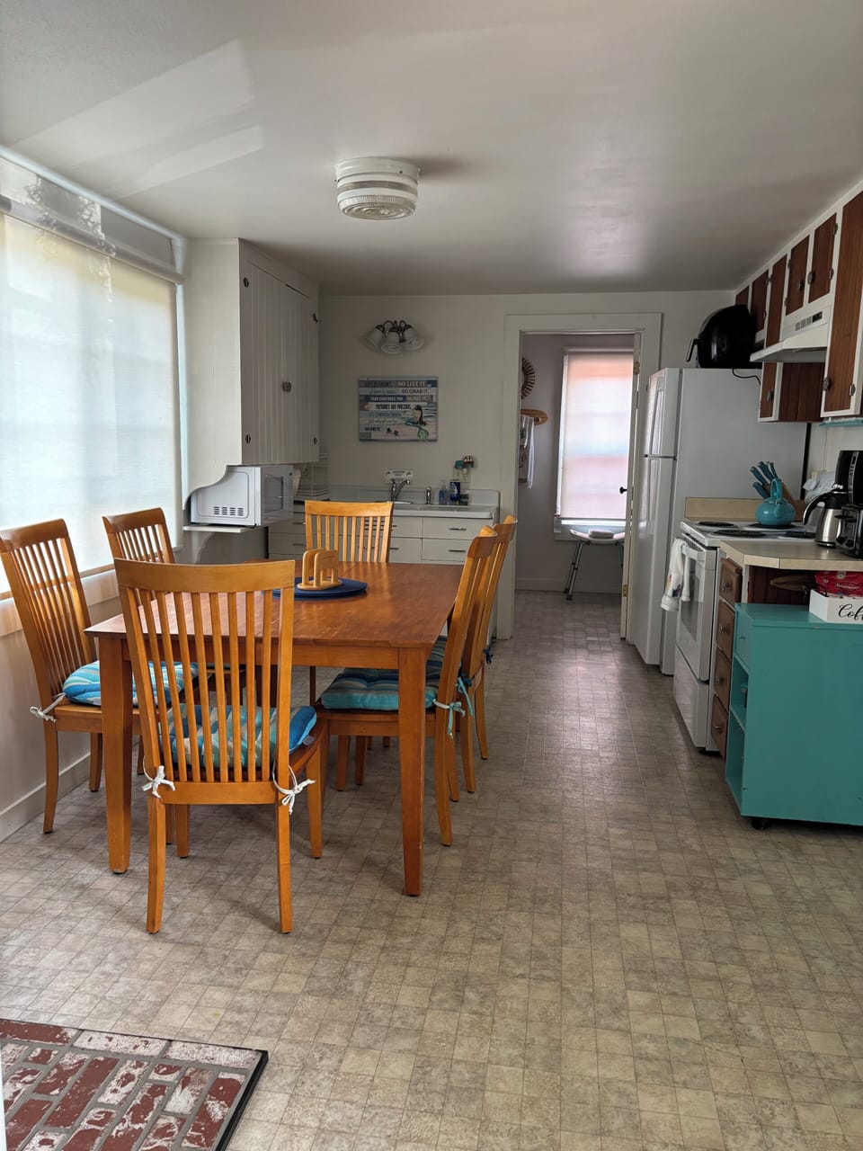 Your open-concept space blends kitchen and dining seamlessly, with warm wood furniture inviting you to gather for meals. Sunlight filters through while modern appliances stand ready for your use.