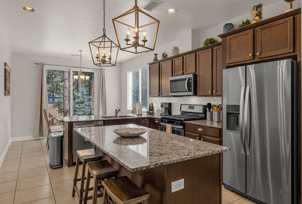 Kitchen with high end stainless steel appliances, island and 3 bar stools.