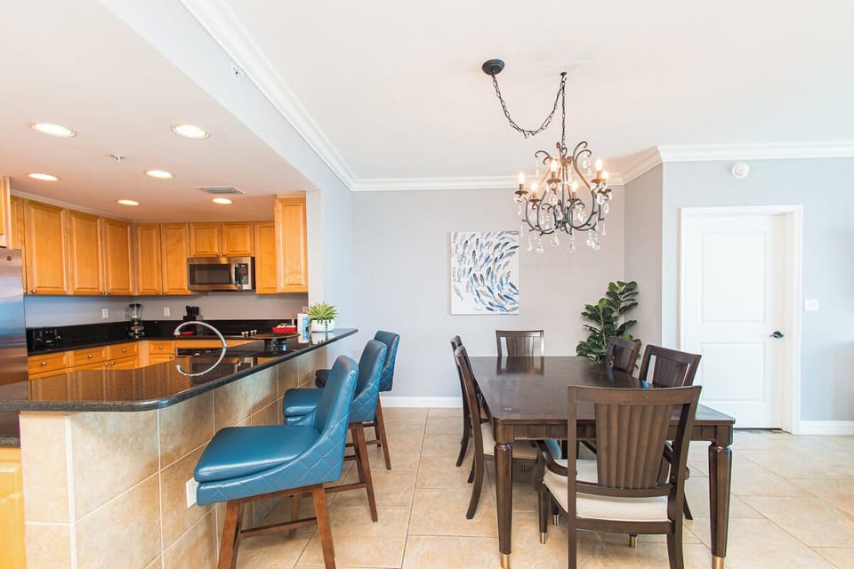 Gather around this elegant dining space featuring coastal-inspired artwork, a chandelier overhead, and an open kitchen. You'll enjoy shared meals in this welcoming, light-filled setting designed for memorable moments.