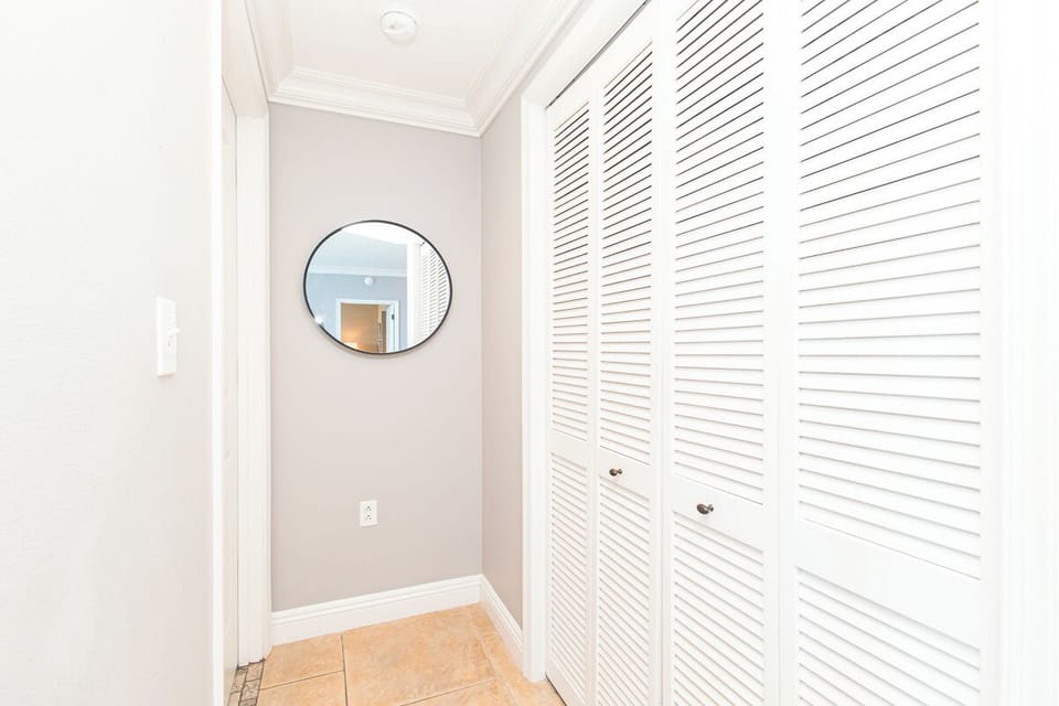 Step into your private hallway—a soft, neutral palette meets smart storage behind elegant louvered doors, with a handy mirror ensuring you're ready for the day.