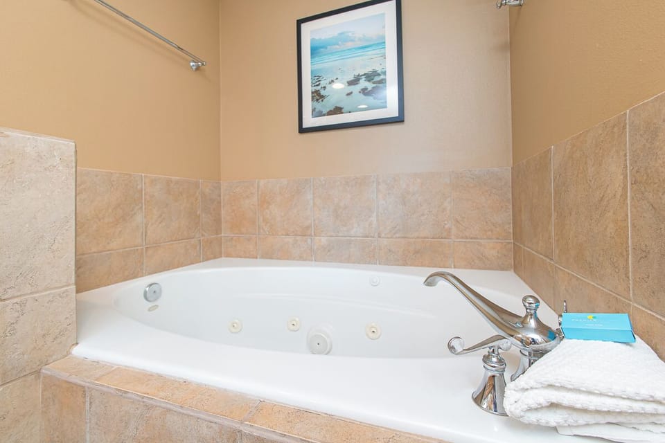 Slip into your private jetted tub surrounded by elegant tile and serene coastal artwork—your personal spa awaits after every adventure.