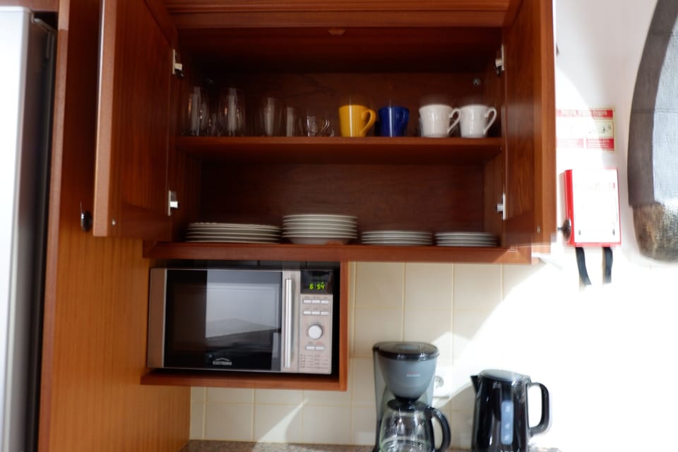 Full kitchen with dishes, microwave, kettle and coffee machine