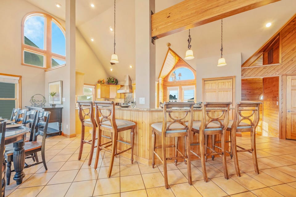 Your spacious kitchen invites gathering with its warm wood beams, granite island seating, and soaring ceilings flooded with natural light.