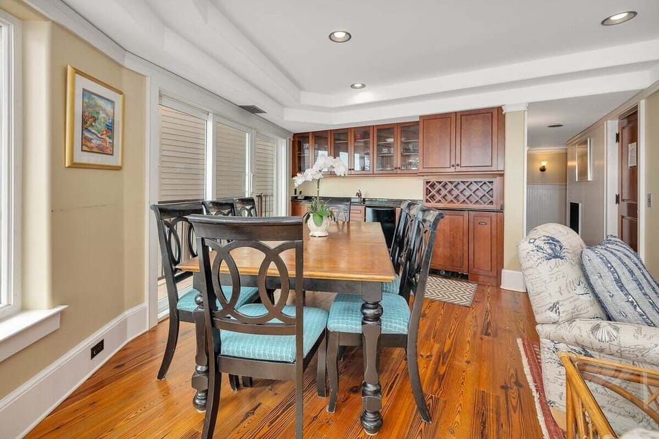 Dining area with wood table, teal chairs, and kitchen beyond