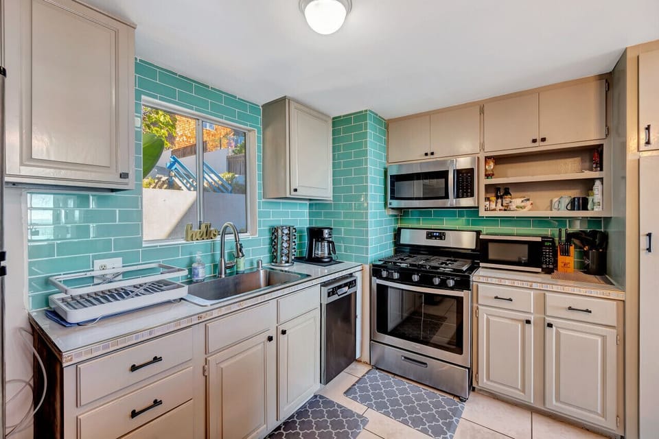 Charming kitchen w/ teal tile backsplash, open shelving & stainless appliances