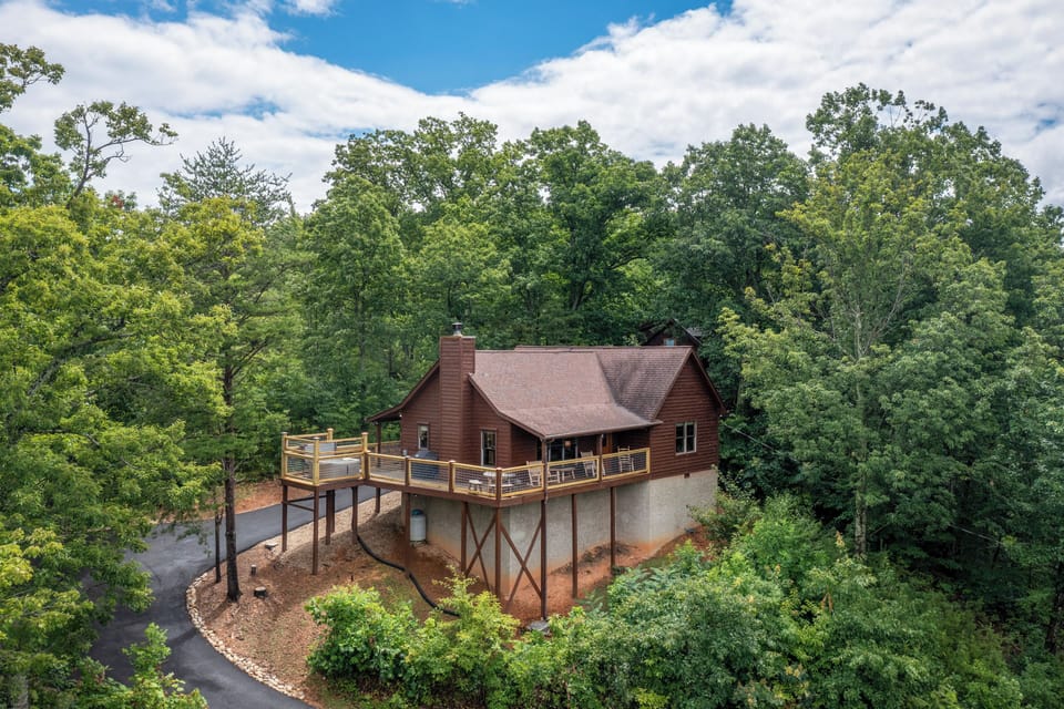 Elevated cabin nestled in lush woodland offers a private mountain escape with spacious deck and scenic forest surroundings.