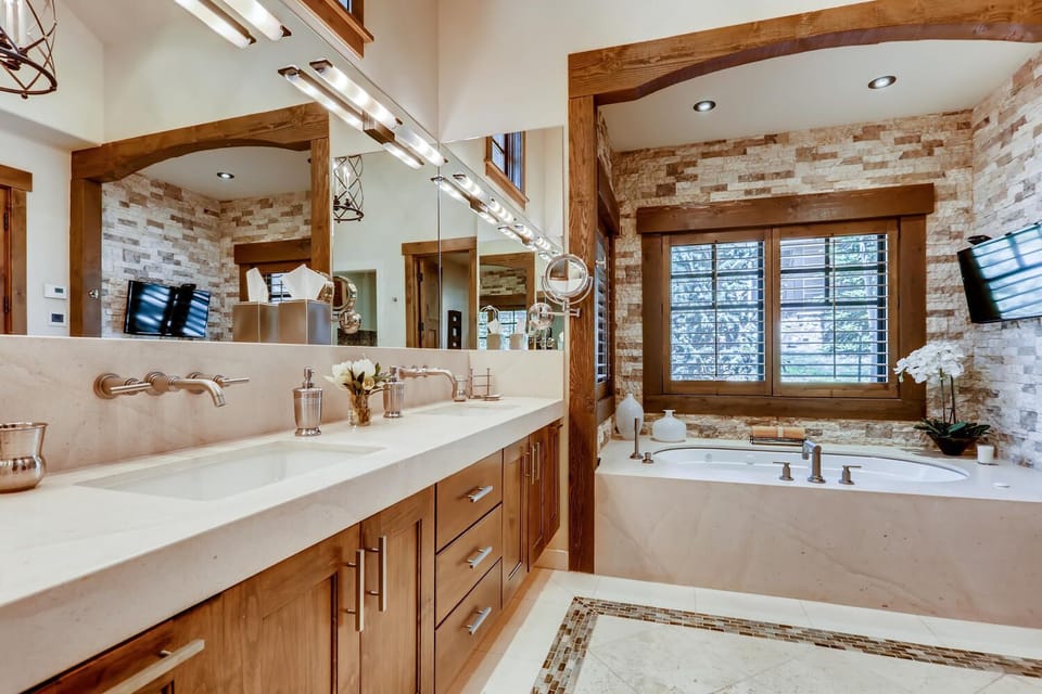 Ground floor primary bathroom with an oversized jacuzzi tub, double sink countertop, and wall-length mirror.