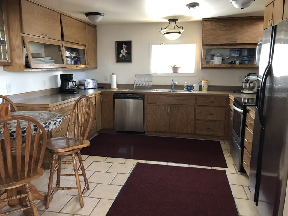 Warm tile floor in modern well equipped kitchen with pub table