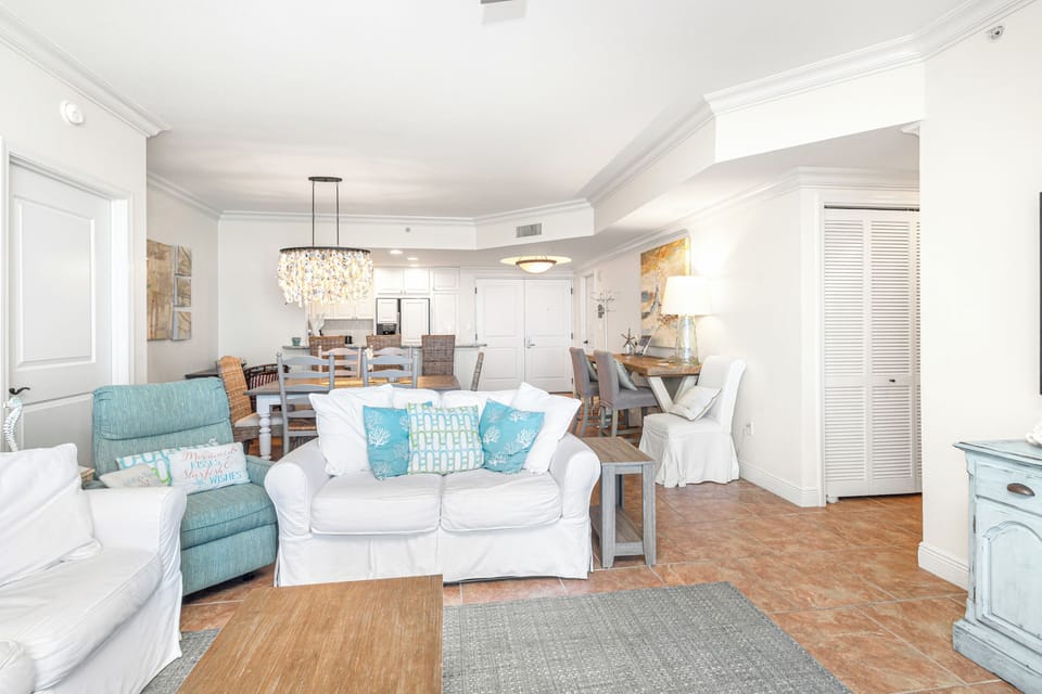Relax in your bright coastal living space with soft turquoise accents and elegant chandelier lighting.