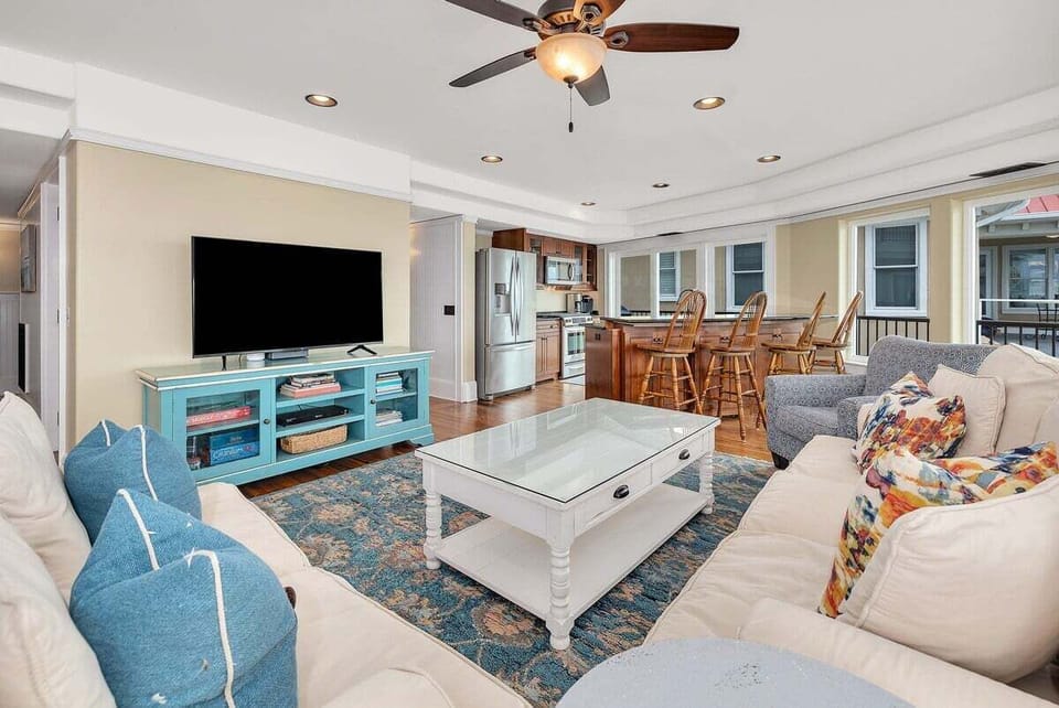 Living room angle showing teal media console, large TV, kitchen
