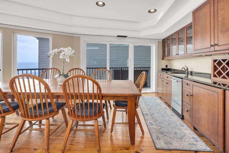 Dining area with wood table, chairs, kitchen, ocean view