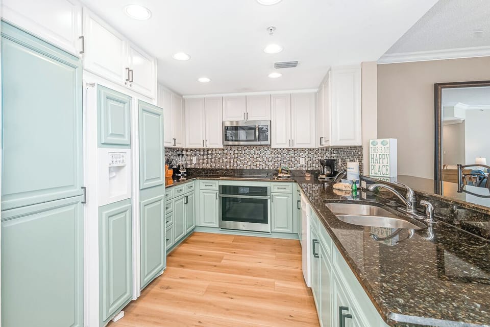 Your fully-equipped kitchen awaits with granite counters, modern appliances, and stylish mint-green cabinets—perfect for preparing memorable meals during your stay.