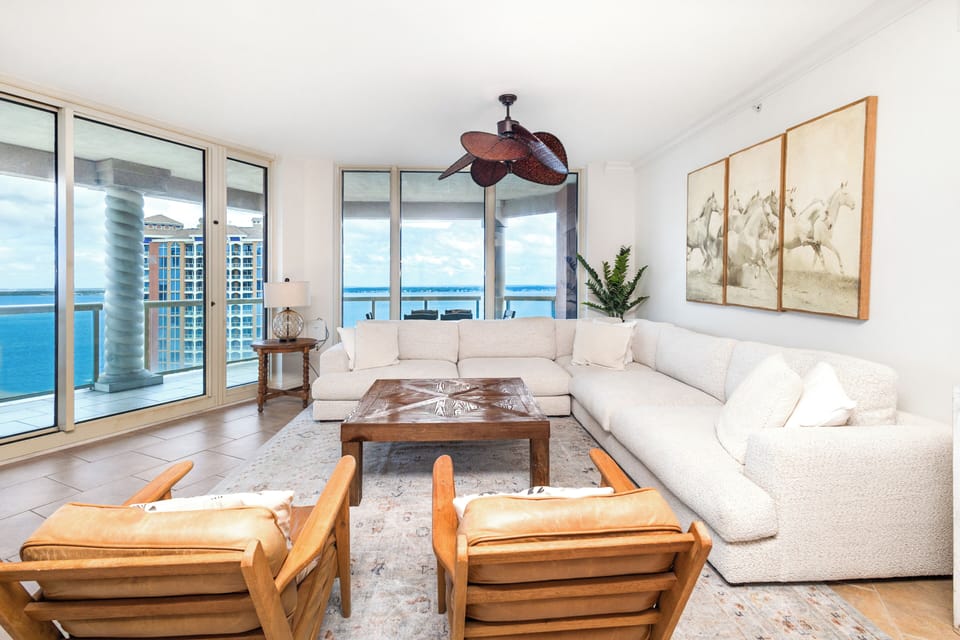 Settle into plush seating in your coastal living room, where floor-to-ceiling windows frame stunning ocean views and soft breezes drift through your private terrace doors.
