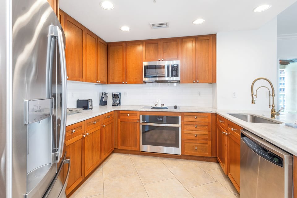 Your gourmet kitchen awaits with warm wood cabinetry, stainless steel appliances, and sleek countertops—ready for morning coffee or a home-cooked meal.