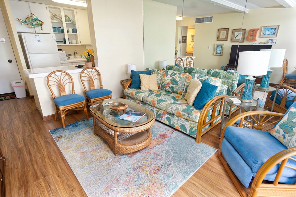 Bright living room with oceanfront seating, queen sofa bed, and floor-to-ceiling views of the Pacific.