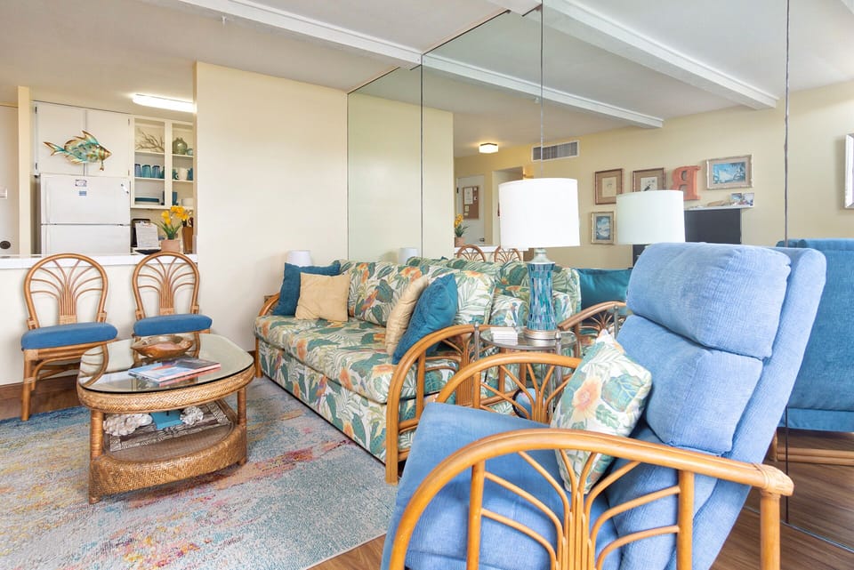 Bright living room with oceanfront seating, queen sofa bed, and floor-to-ceiling views of the Pacific.