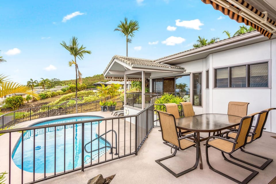 Outdoor dining overlooks the private pool and lush vegetation around the property.