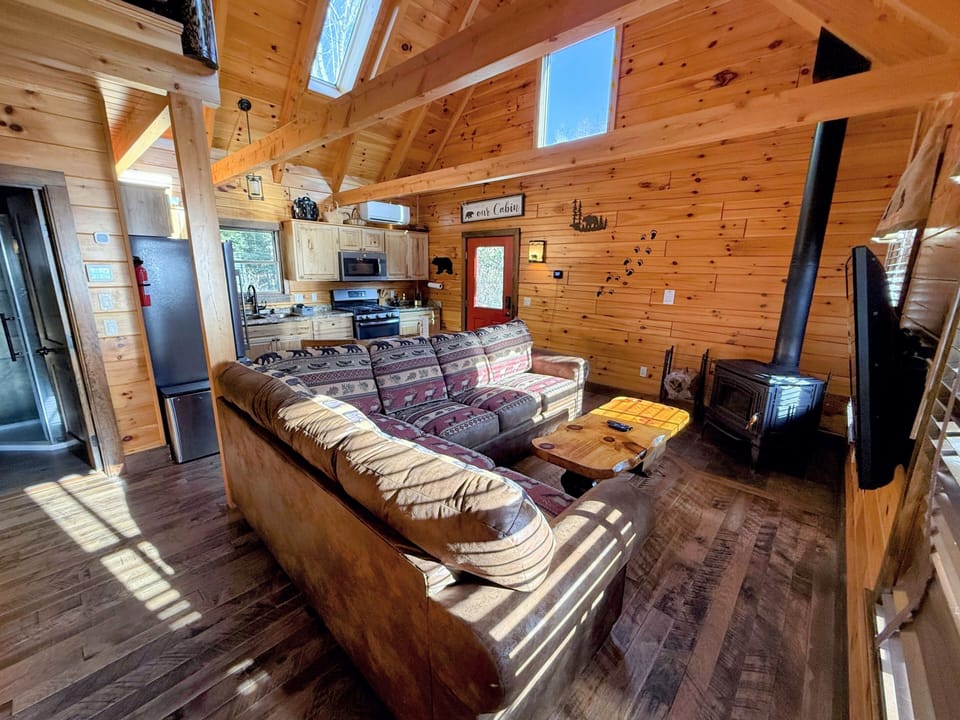 Cabin from front entry with new couch. Small but cozy and comfortable, the main living area includes the kitchen, a small dining table, and a TV area.