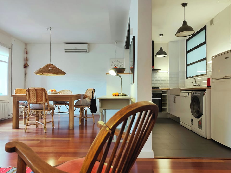 Relax in the stylish open-plan living space, where warm wooden floors and natural textures meet a sleek, modern kitchen.