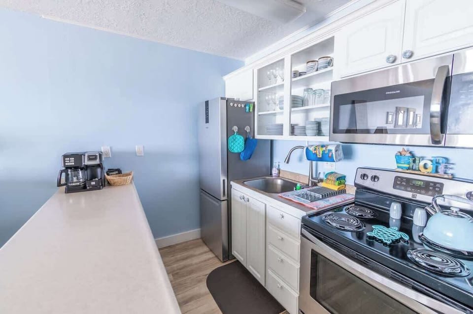 The kitchen is fully equipped with a fridge, stove, oven, and microwave