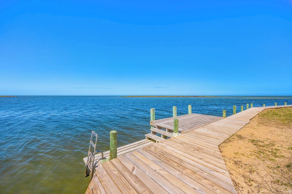 A private wooden dock extends over calm waters under clear blue skies—your perfect launch point for kayaking, fishing, or simply soaking in the peaceful waterfront setting.