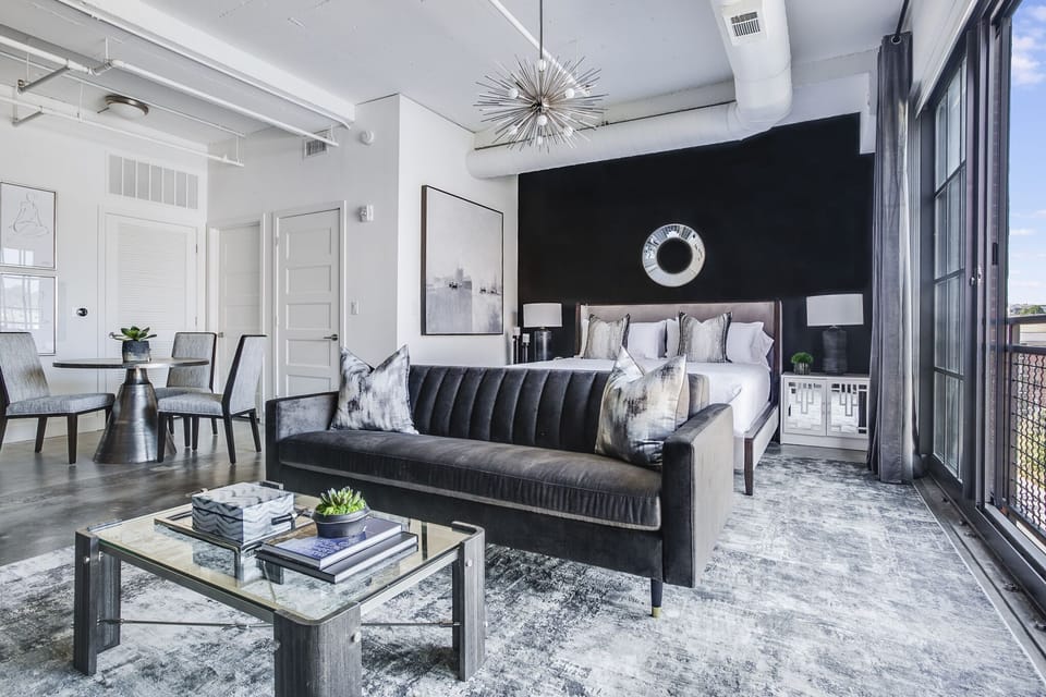 Living area with large bed, sofa, coffee table, and a table with chairs in the corner.