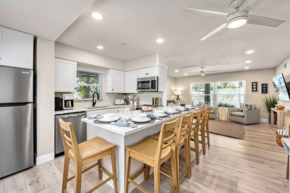 Spacious layout includes a sleeper sofa, TV console, and views into the bright kitchen and breakfast bar.