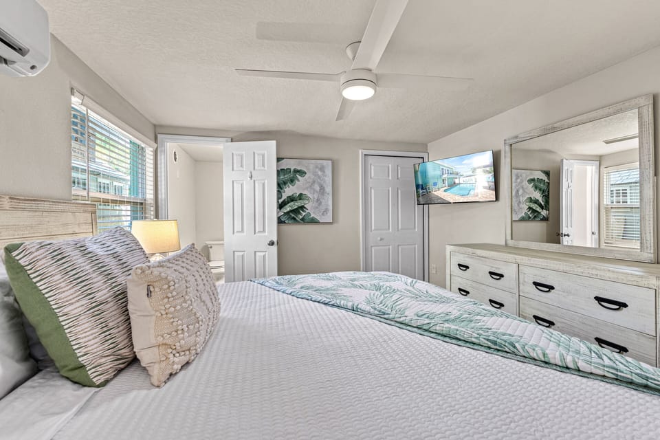 A comfortable and stylish room with soft bedding, calming tones, and a wall-mounted smart TV.