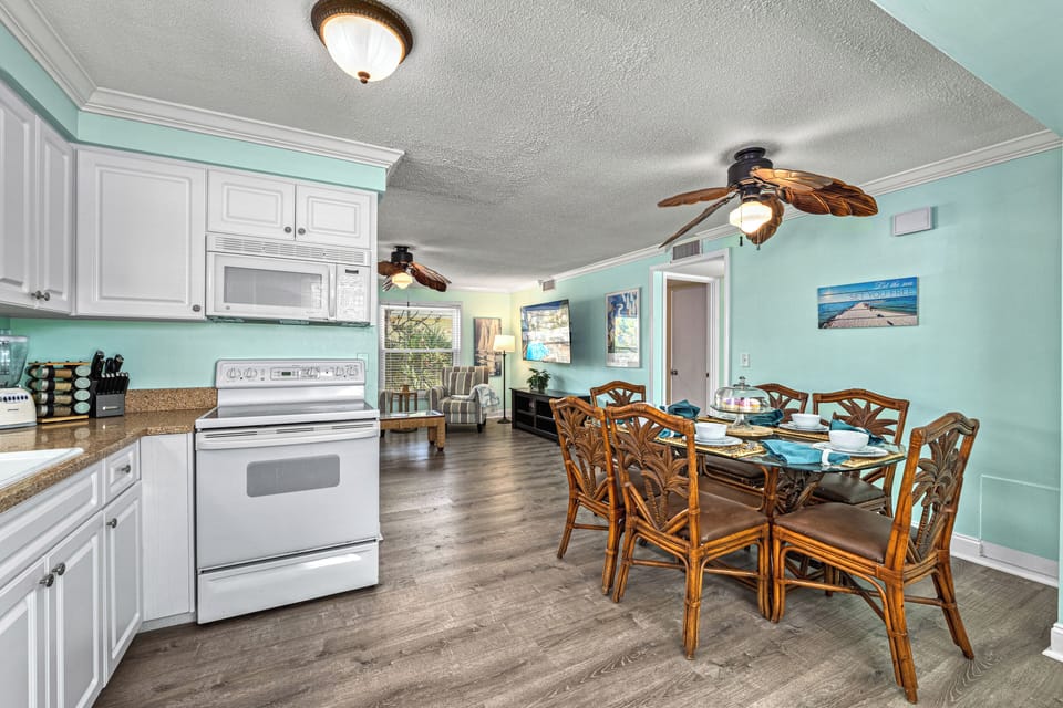 Wide-angle shows the full kitchen setup with social space beyond.
