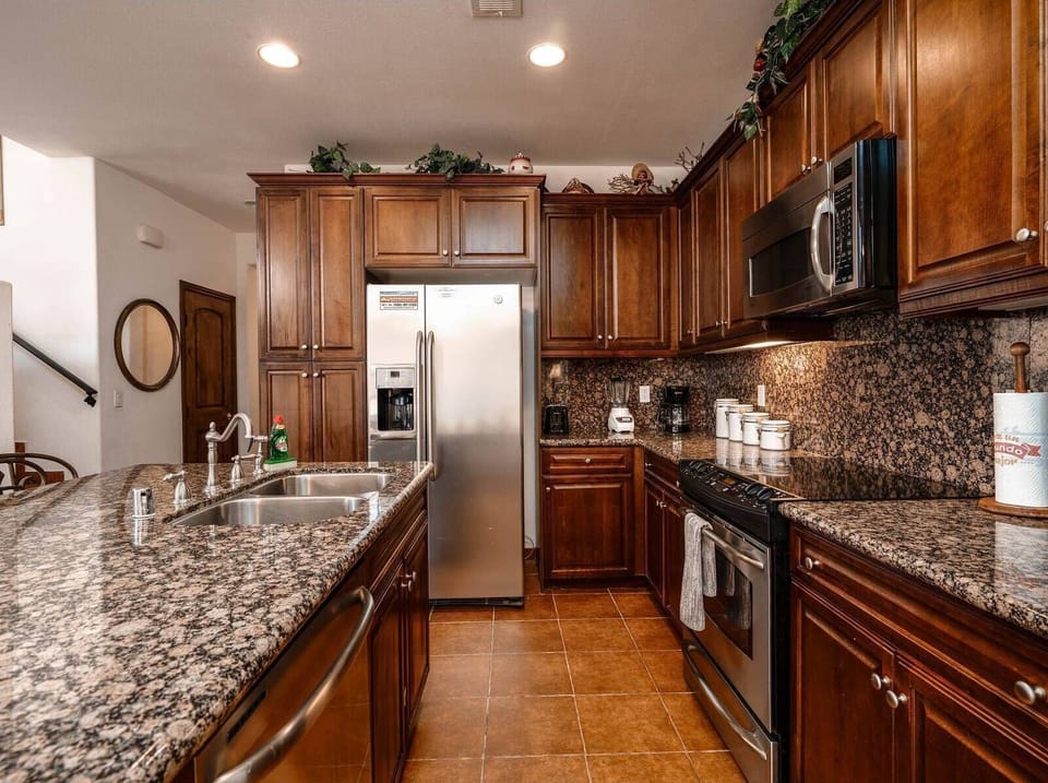 Fully equipped kitchen with refrigerator, stove, microwave, dishwasher, and coffee maker — opens to dining and living areas.