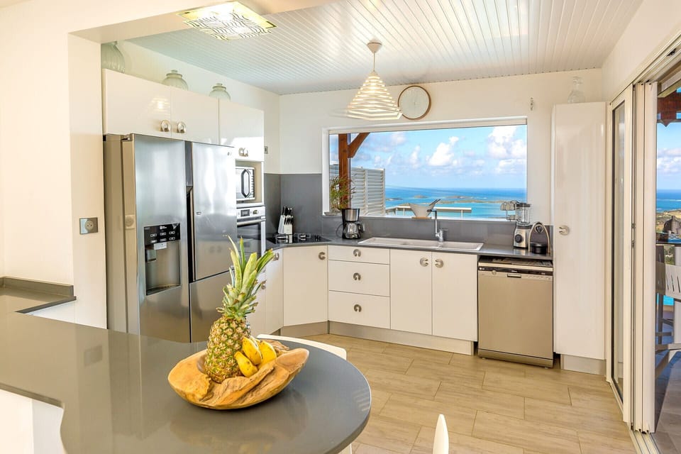 Villa Lidoam's modern and functional kitchen is extended by a bar opening onto the terrace, ideal for entertaining friends and family with a view of the ocean.