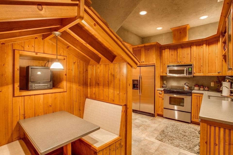 Rustic wood-clad kitchen with cozy breakfast nook and stainless appliances