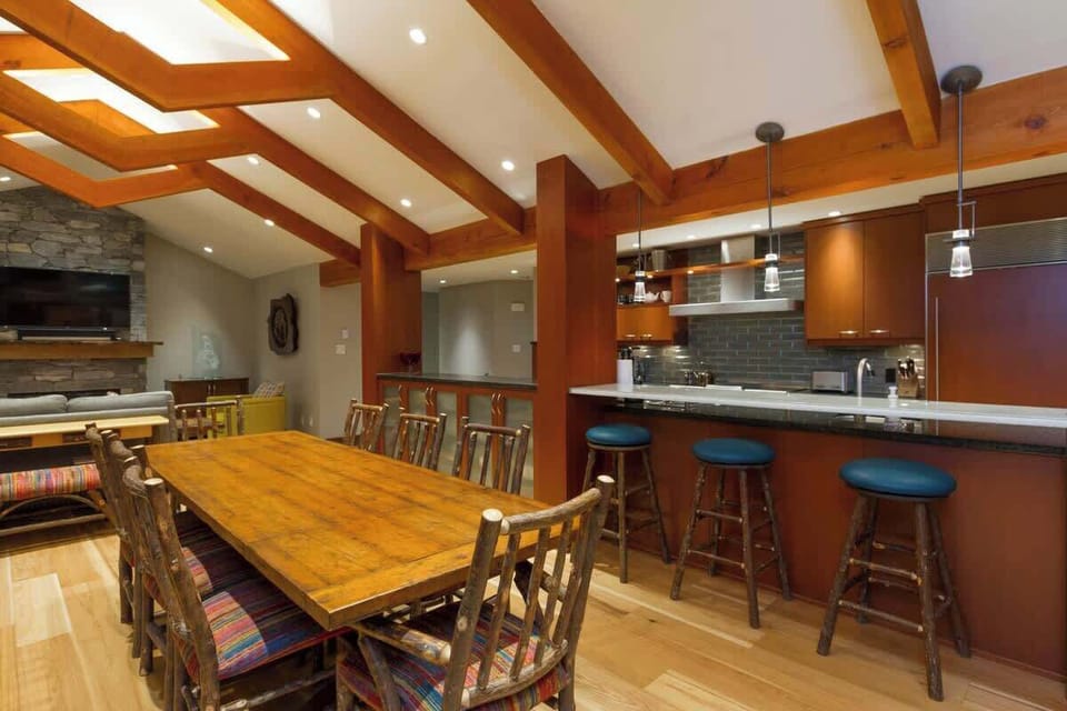 - Spacious dining room with rustic wooden table and seating for family gatherings  
- High ceilings with exposed beams create a warm alpine atmosphere  
- Connects seamlessly to the kitchen and living area for shared moments  

