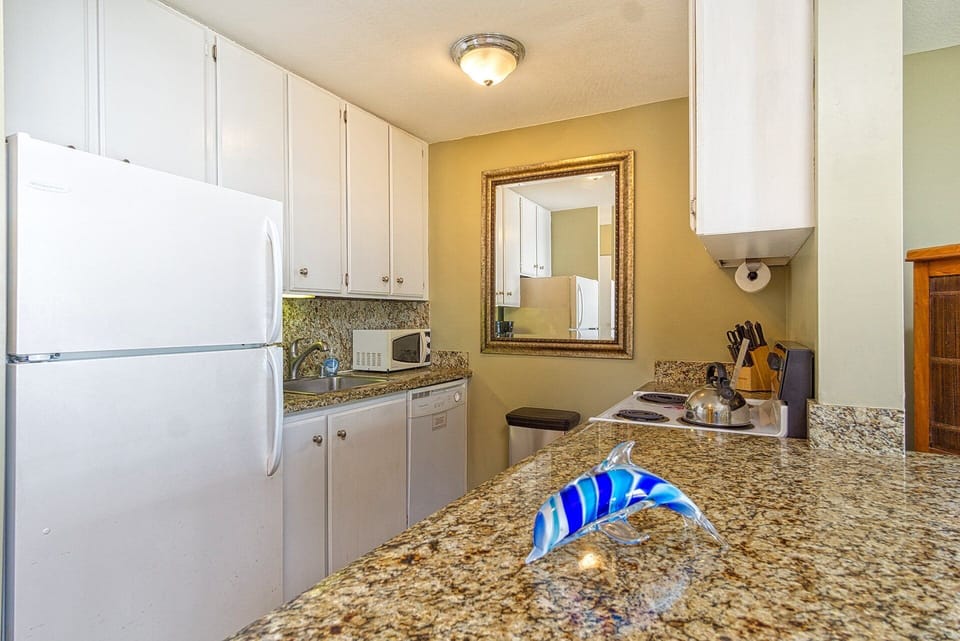 Cook meals with ease in the kitchen, featuring appliances, cookware, and a pass-thru to the ocean-view.