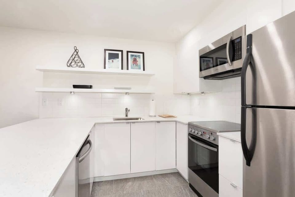 - Sleek white kitchen with stainless steel appliances  
- Fully equipped with cookware for home-style meals  
- Spacious counters and bright lighting for easy prep  
