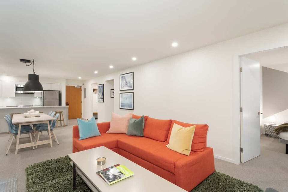- Cozy living area with bright orange sofa for relaxing  
- Open-concept layout connects living, dining, and kitchen  
- Modern decor and soft lighting create a welcoming stay  