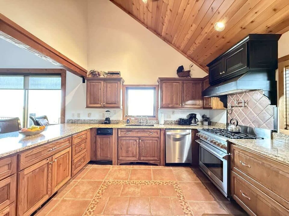 Large kitchen equipped with stainless steel appliances, pots and pans, dishes, utensils, and cooking essentials.