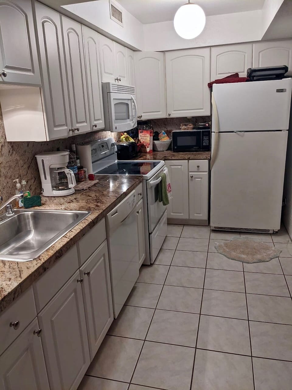 The kitchen area of the unit, fully stoked with dish ware and appliances. 