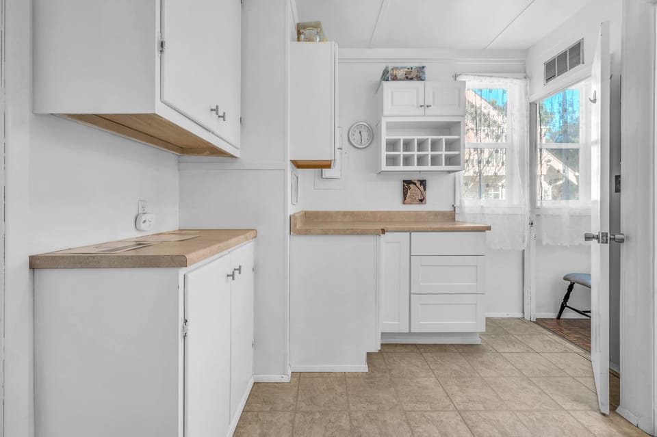 Your bright, fully-equipped kitchen awaits with warm wood countertops, white cabinetry, and natural light streaming through windows.