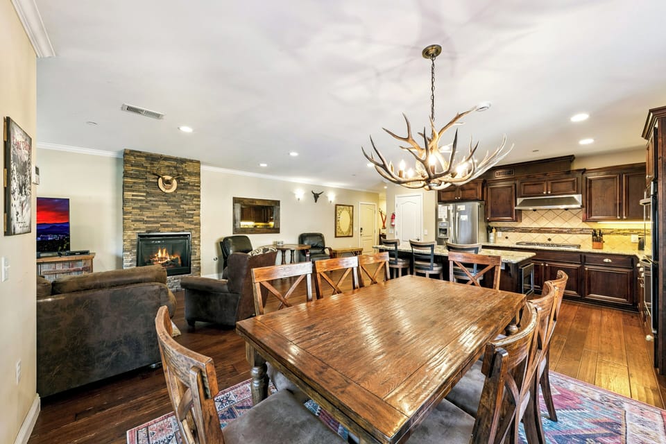 Gather around your expansive dining table beneath the stunning antler chandelier, while the stone fireplace crackles nearby and your gourmet kitchen awaits.